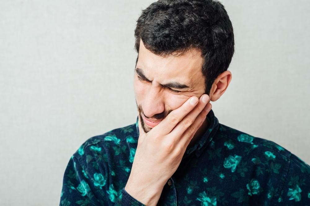 Man holding his cheek with tooth pain